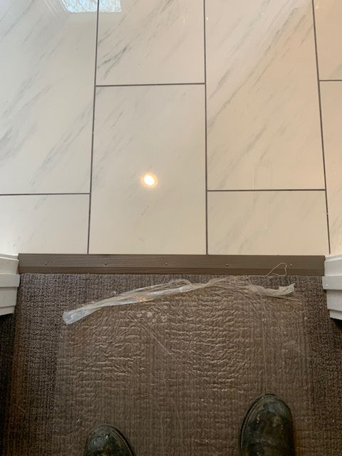 A person is standing on a tiled floor next to a door.