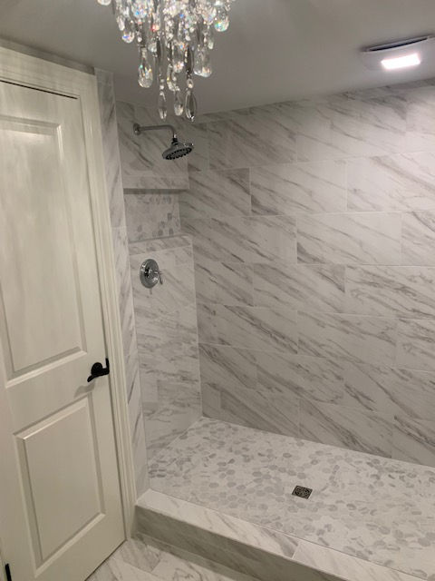 A bathroom with a shower and a chandelier hanging from the ceiling.