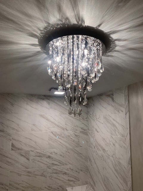 A large chandelier is hanging from the ceiling in a bathroom.