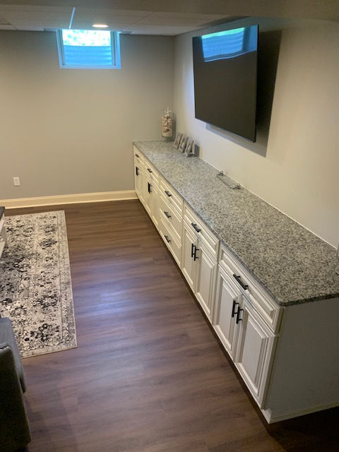 A room with a long counter and a flat screen tv on the wall.