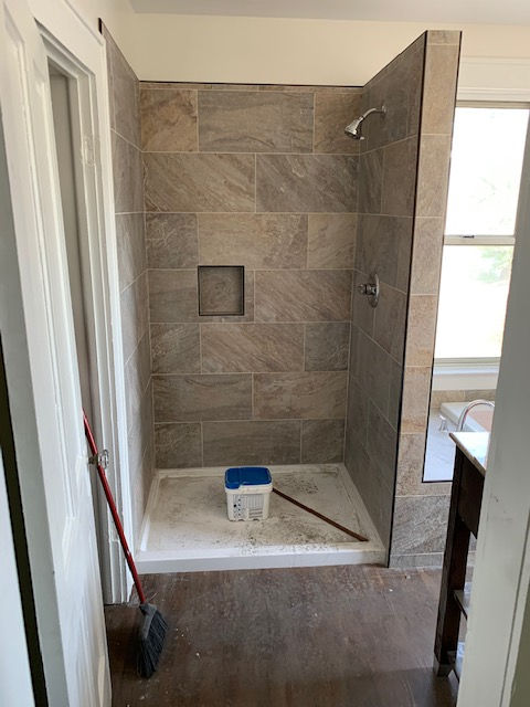 A bathroom with a walk in shower and a broom