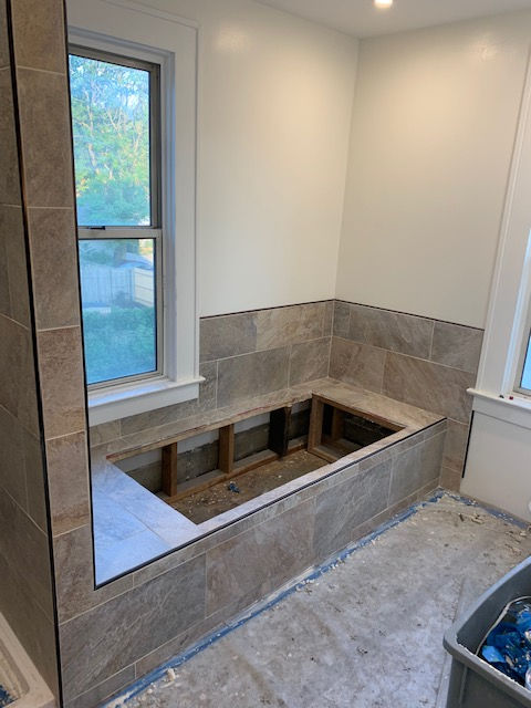 A bathtub is being built in a bathroom next to a window.