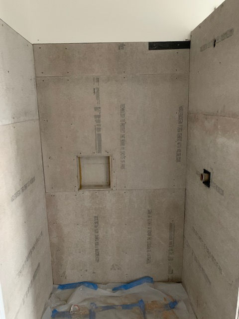 A bathroom with a shower stall and a niche in the wall.