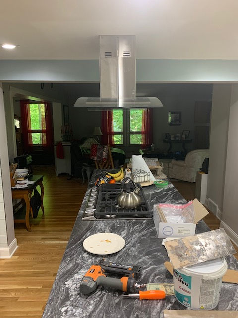 A kitchen with a stove top oven and a hood.