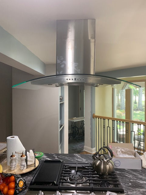 A kitchen with a stove top oven and a stainless steel hood