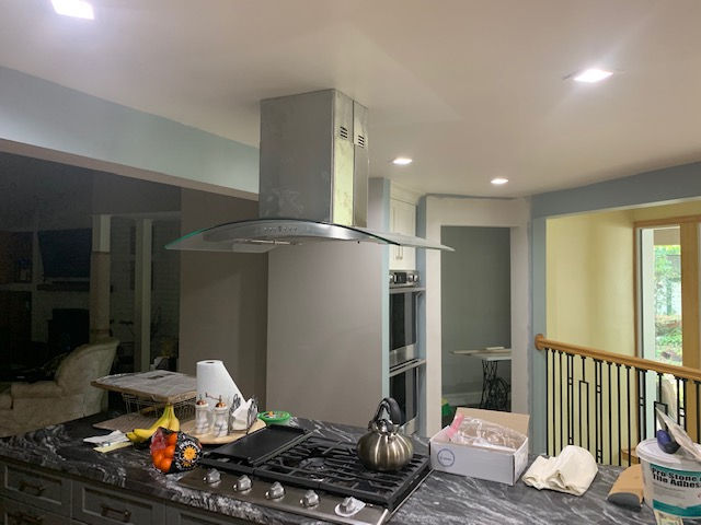 A kitchen with a stove top oven and a hood.