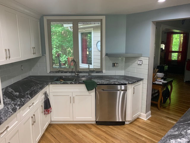 A kitchen with white cabinets and a stainless steel dishwasher