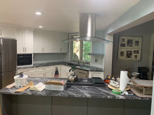 A kitchen with a stove top oven and a hood.