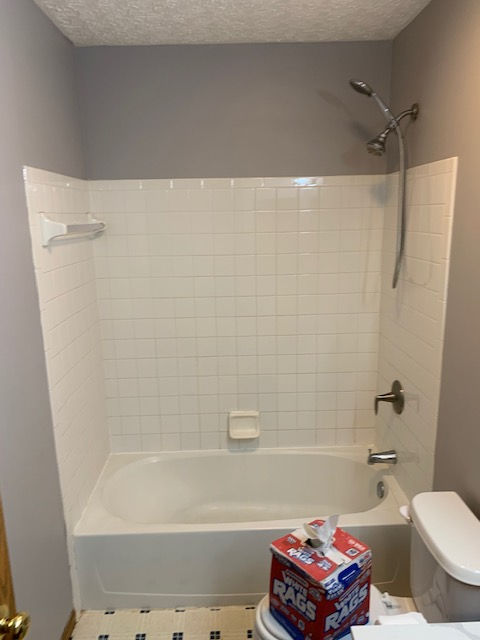 A bathroom with a tub , toilet and shower.