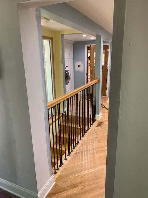 A hallway with stairs and a railing in a house.