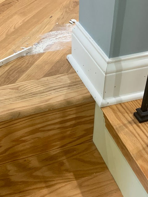 A close up of a wooden floor with a white trim