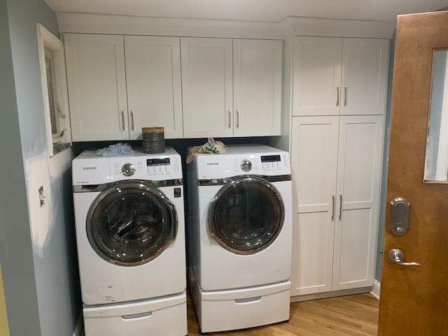 A laundry room with two white washers and dryers