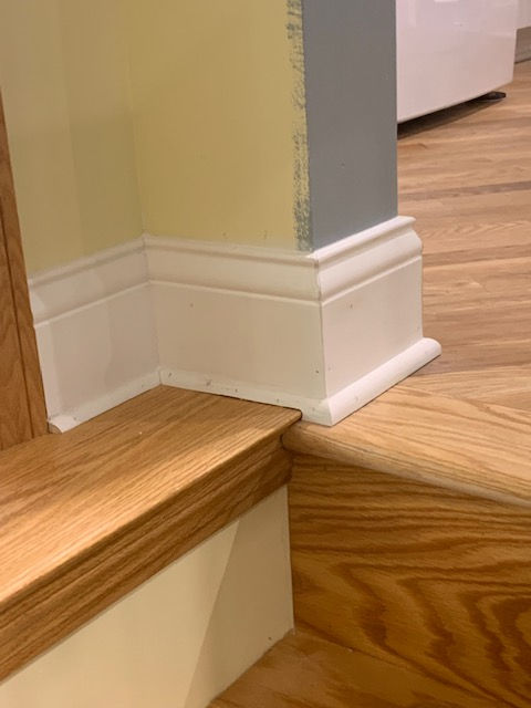 A wooden staircase with white molding and a yellow wall