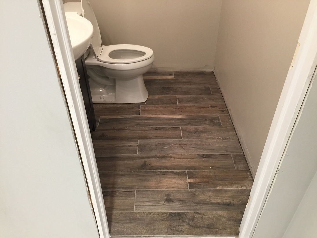 A bathroom with a toilet , sink and wooden floor.