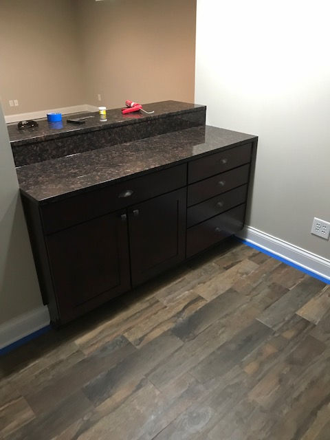 A bathroom with hardwood floors and a vanity with a granite counter top.