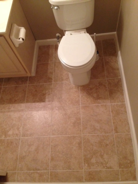 A toilet sits on a tiled floor in a bathroom