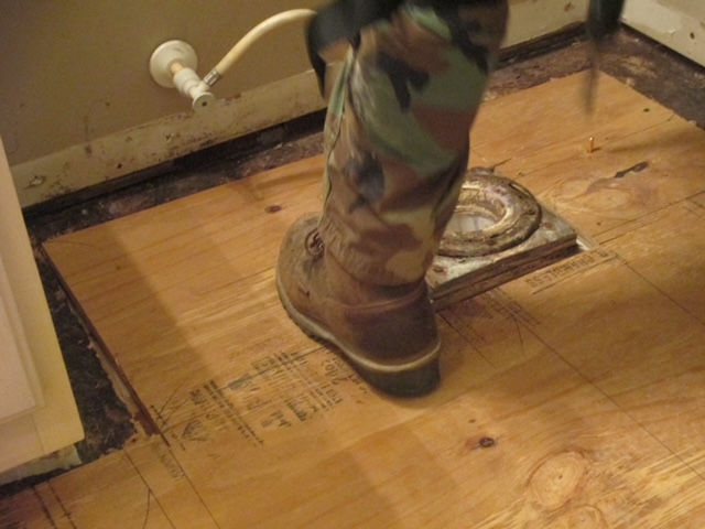 A person wearing camouflage boots is standing on a wooden floor