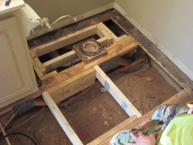 A person is working on the floor of a bathroom.