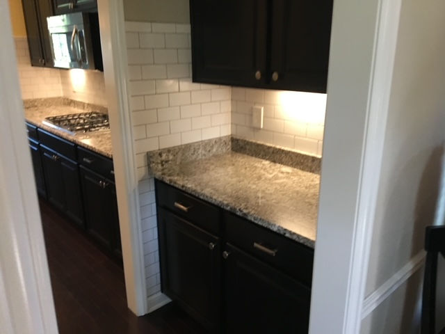 A kitchen with black cabinets and granite counter tops