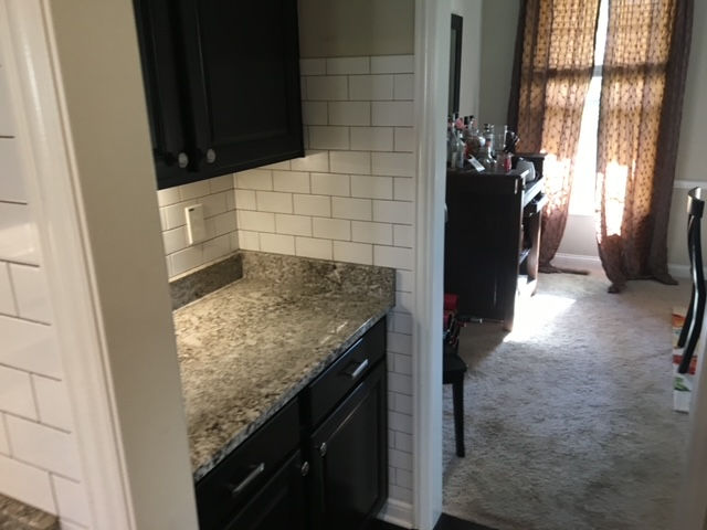 A kitchen with black cabinets and granite counter tops.