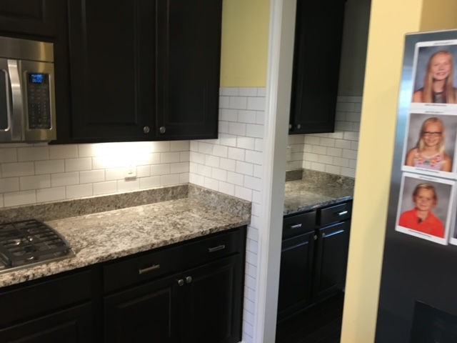 A kitchen with black cabinets and granite counter tops