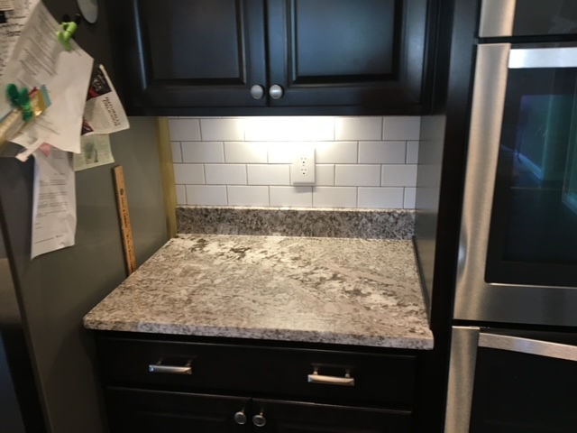 A kitchen with black cabinets and a granite counter top