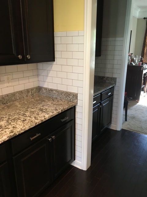 A kitchen with black cabinets and granite counter tops