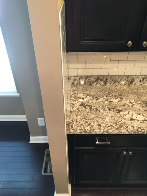 A kitchen with granite counter tops and black cabinets