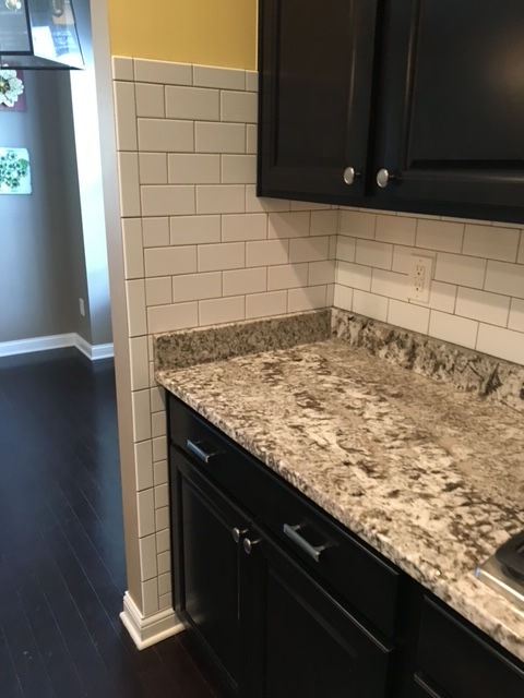 A kitchen with granite counter tops and black cabinets