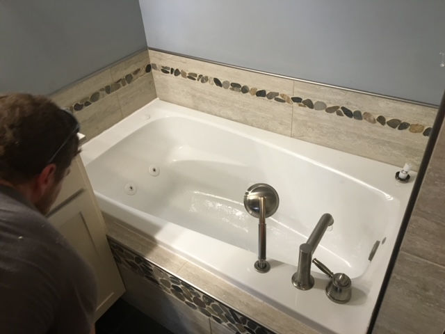A man is standing next to a bathtub in a bathroom.