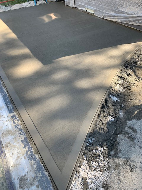 A concrete driveway is being built next to a tree.