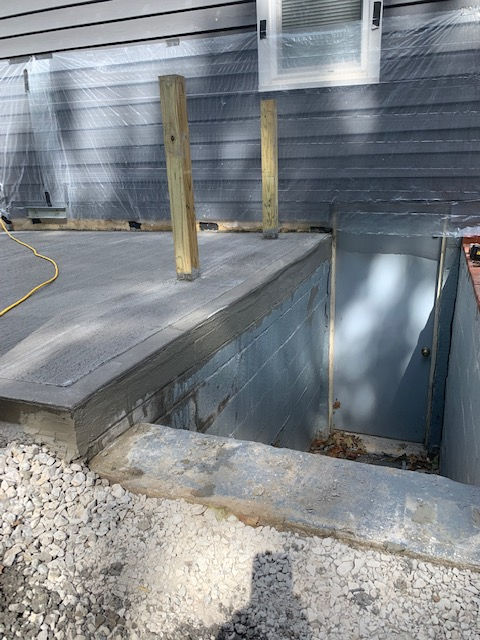 A concrete deck is being built in front of a house.