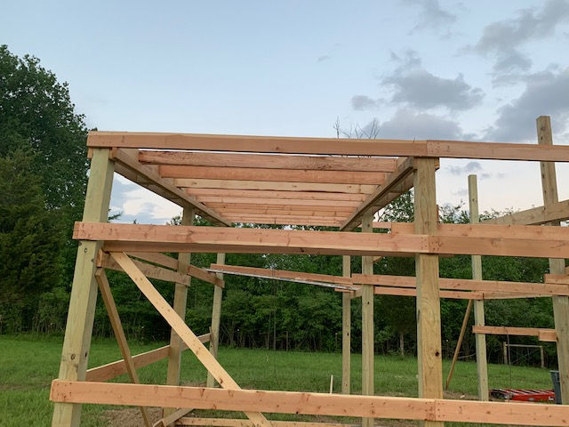 A wooden structure is being built in a field