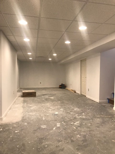 An empty basement with a concrete floor and white walls.