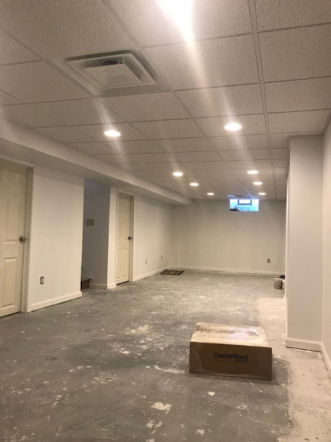 An empty basement with white walls and a box on the floor.