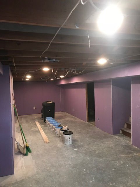 A basement with purple walls and a wooden ceiling.