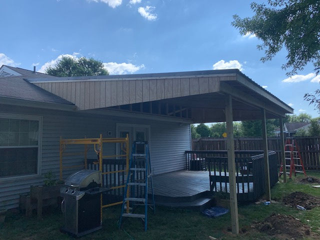 A covered deck is being built in the backyard of a house.