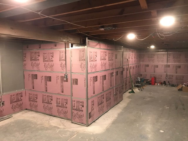 A basement with a lot of pink insulation on the walls.