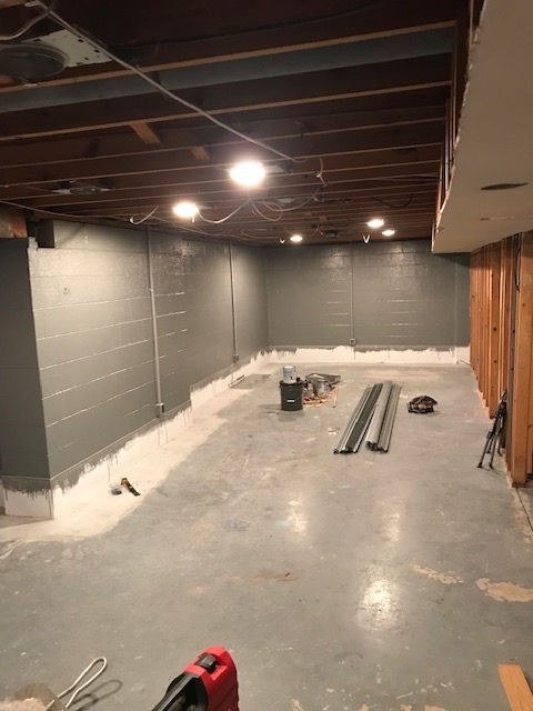 A basement under construction with a vacuum cleaner in the middle of the room.