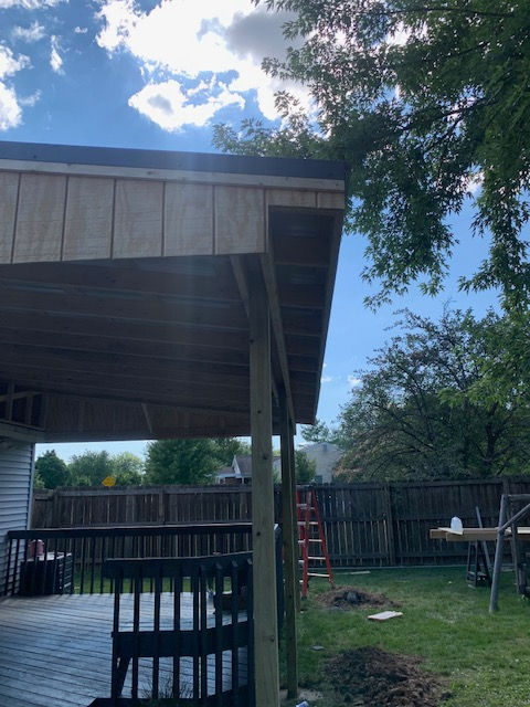 A carport is being built in the backyard of a house.