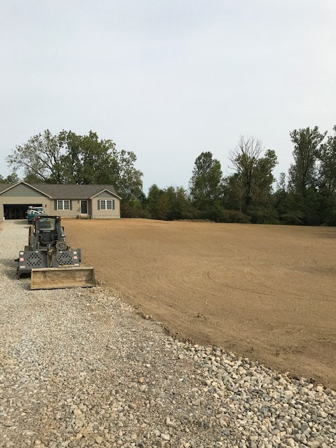 A gravel driveway with a house in the background