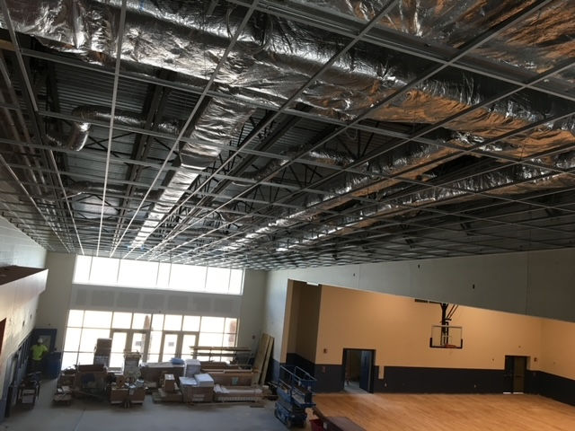 A basketball hoop is hanging from the ceiling of a building under construction.