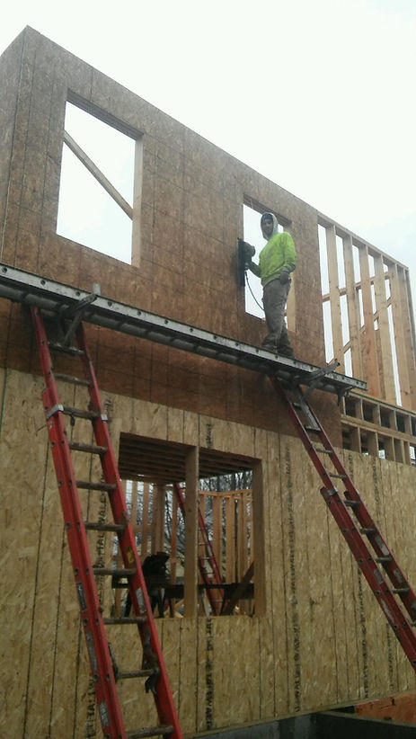 A man is standing on a ladder on top of a building under construction.