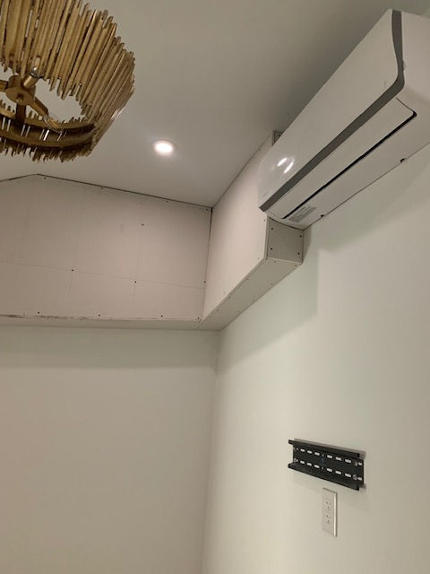 A room with a chandelier and an air conditioner on the wall