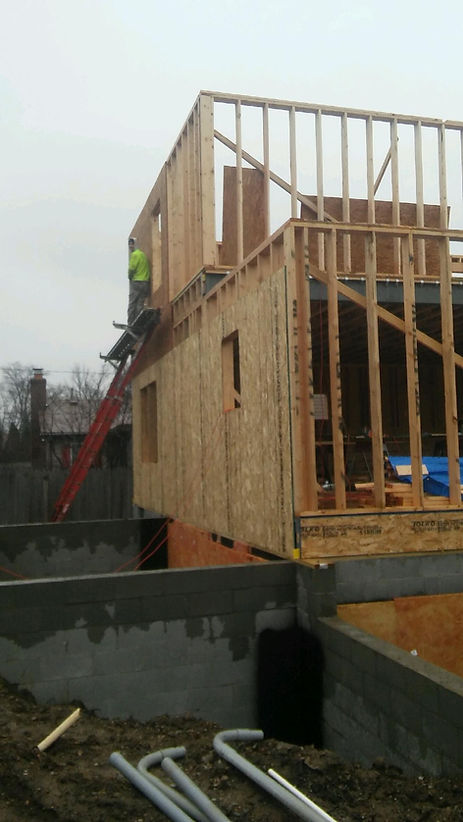 A man is standing on a ladder on top of a building under construction