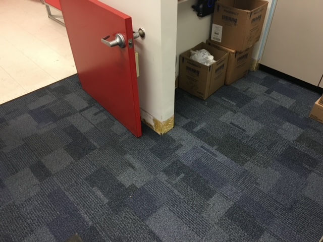 A room with boxes on the floor and a red door