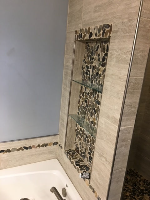 A bathroom with a bathtub and a shelf in the wall.