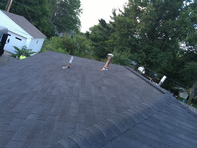 A roof with a chimney on it and trees in the background