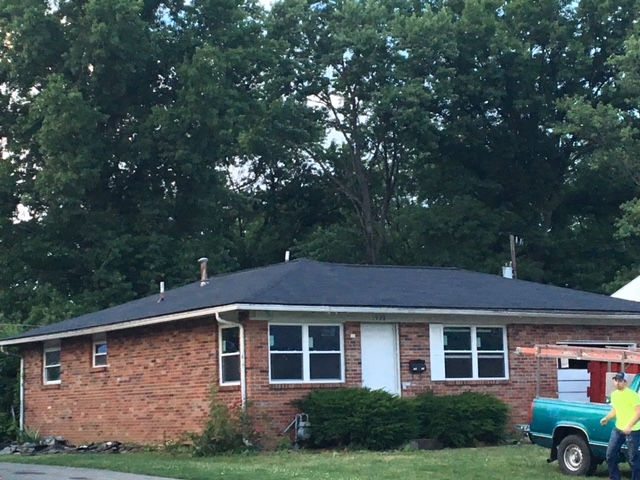 A brick house with a blue truck parked in front of it
