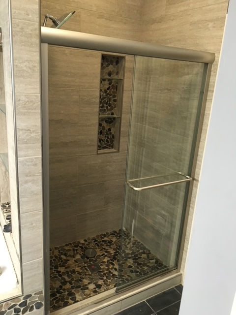 A bathroom with a sliding glass shower door and a tiled floor.